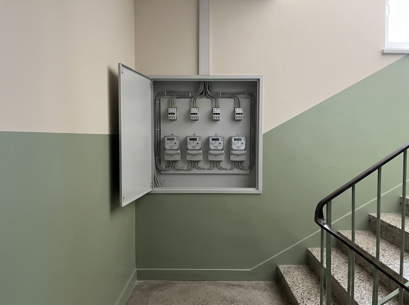 Otwarta szafka z licznikami energii elektrycznej na klatce schodowej bloku