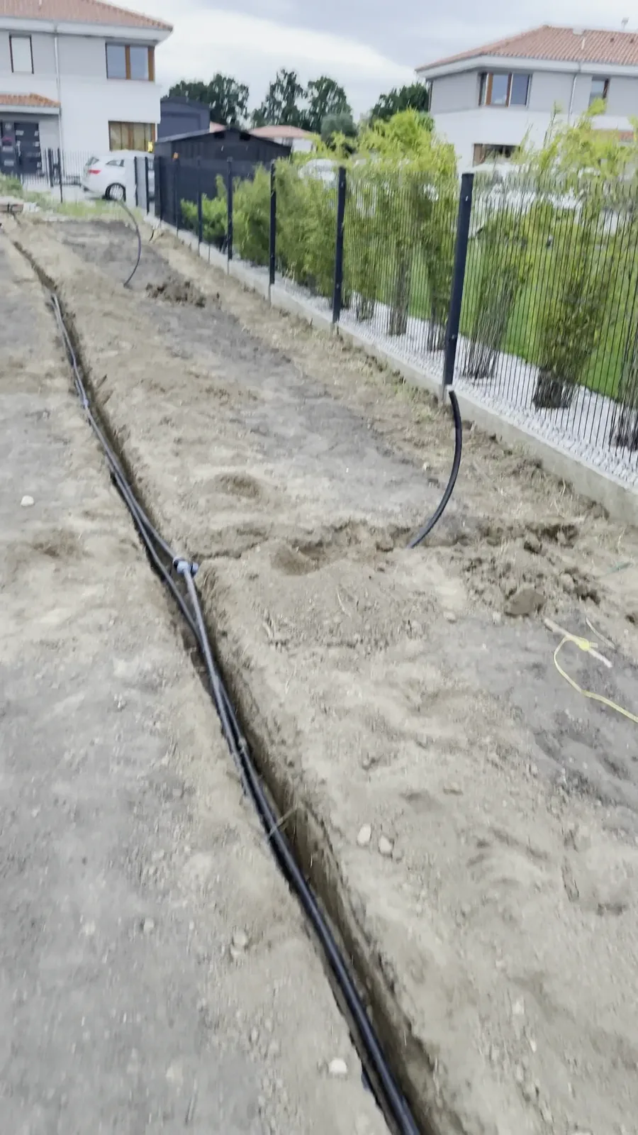 Układanie rur PE w rowku przed zasypaniem - montaż nawadniania w Kościnie